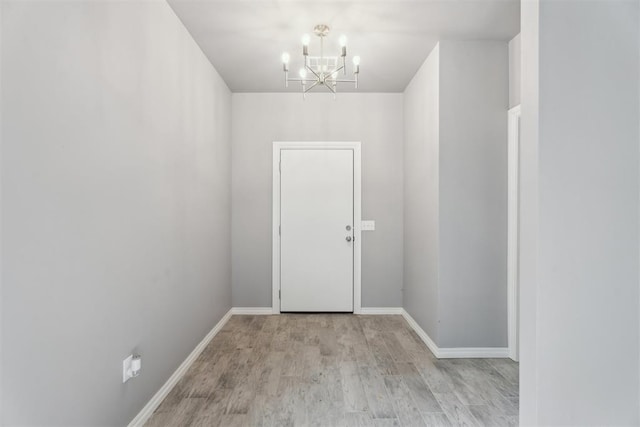 entryway with baseboards, wood finished floors, and a notable chandelier