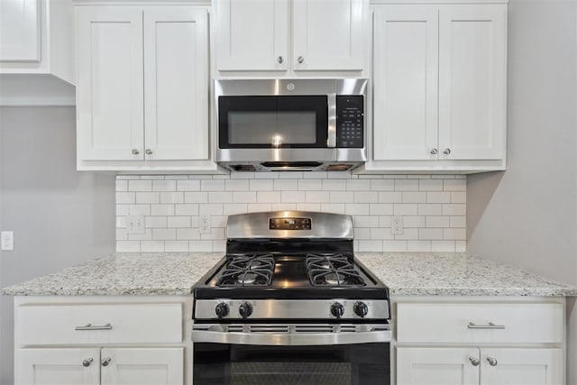 kitchen featuring appliances with stainless steel finishes, white cabinets, light stone countertops, and backsplash