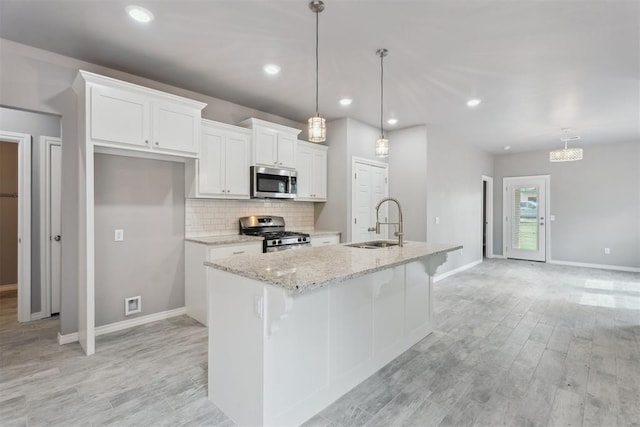 kitchen with baseboards, a sink, appliances with stainless steel finishes, and white cabinets
