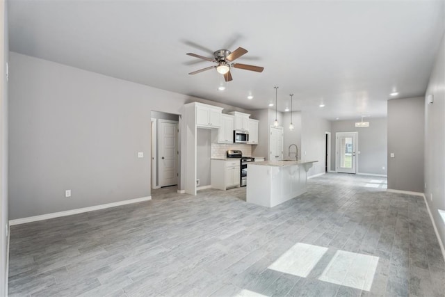 kitchen with open floor plan, ceiling fan, white cabinetry, a sink, and stainless steel appliances