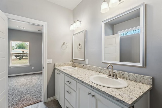bathroom with double vanity, a sink, and baseboards