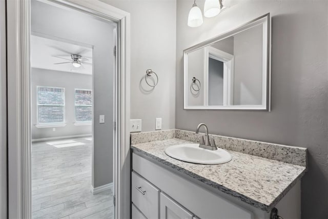 bathroom featuring vanity, ceiling fan, baseboards, and wood finished floors