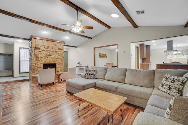 living room with a healthy amount of sunlight, ceiling fan, visible vents, light wood-type flooring, and vaulted ceiling with beams