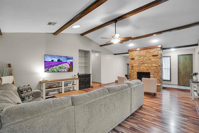 living room with visible vents, wood finished floors, a fireplace, vaulted ceiling with beams, and a ceiling fan