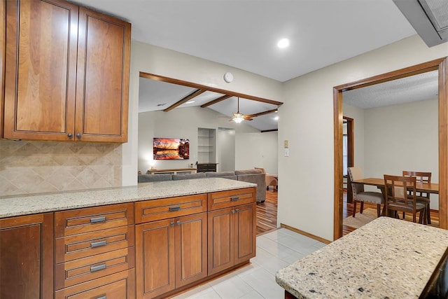 kitchen featuring decorative backsplash, a peninsula, light stone countertops, vaulted ceiling with beams, and brown cabinets