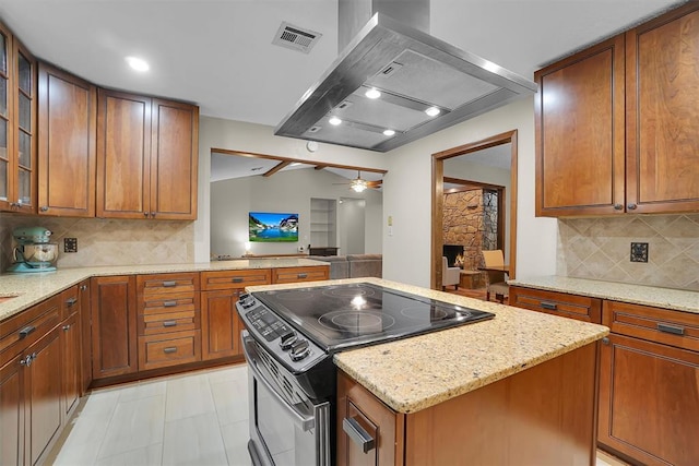 kitchen with light stone counters, wall chimney exhaust hood, a ceiling fan, decorative backsplash, and range with electric stovetop