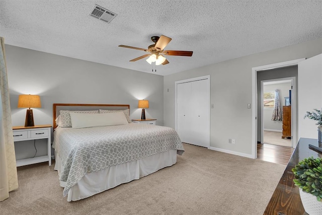carpeted bedroom featuring visible vents, a textured ceiling, baseboards, and a closet