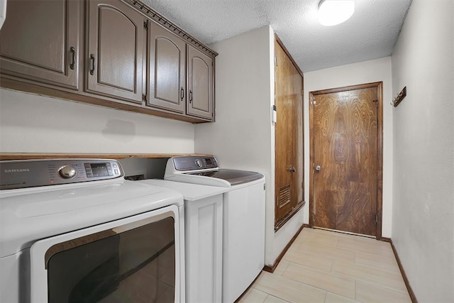 clothes washing area with baseboards, cabinet space, a textured ceiling, and washing machine and clothes dryer
