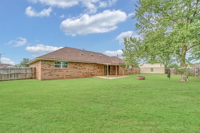 rear view of property featuring a lawn, brick siding, a fenced backyard, a patio, and a shingled roof
