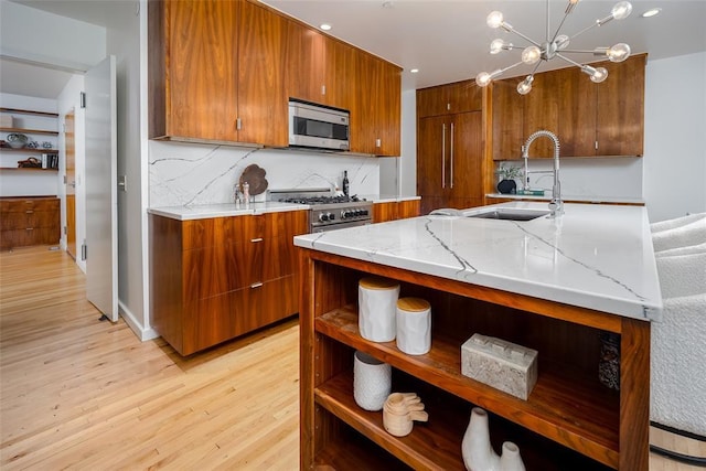1000 NW 37th St Unit 1000 & 1002, Oklahoma City, OK 73118 - kitchen featuring brown cabinetry, appliances with stainless steel finishes, a sink, light stone counters, and light wood-style floors