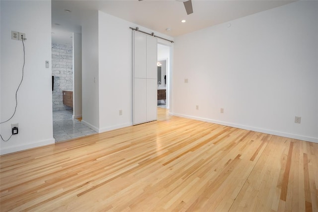 1000 NW 37th St Unit 1000 & 1002, Oklahoma City, OK 73118 - empty room featuring a ceiling fan, baseboards, a barn door, and light wood-style flooring