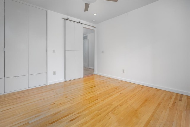 1000 NW 37th St Unit 1000 & 1002, Oklahoma City, OK 73118 - unfurnished bedroom featuring light wood-style floors, a barn door, baseboards, and ceiling fan