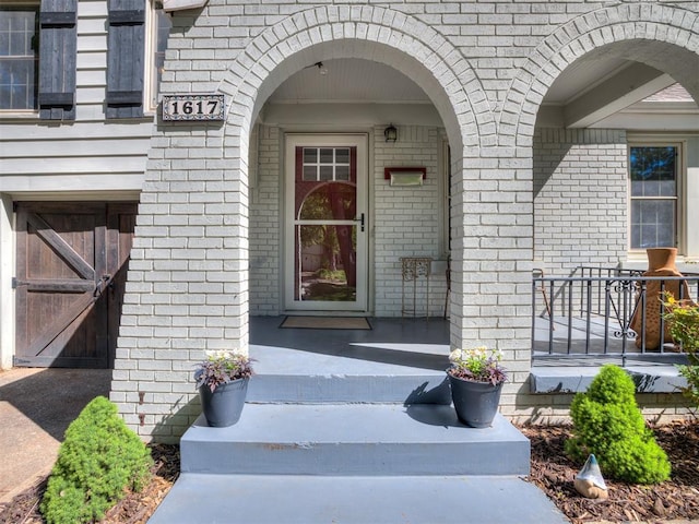 view of exterior entry with covered porch and brick siding
