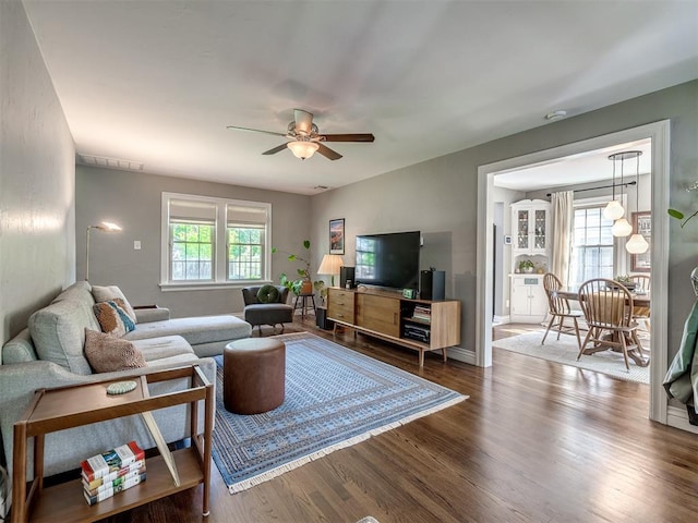 living area featuring a ceiling fan, visible vents, and dark wood-style floors