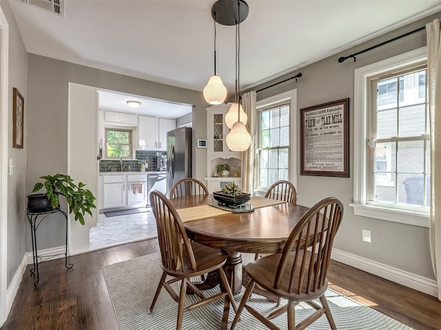 dining room with baseboards, visible vents, a wealth of natural light, and dark wood-type flooring