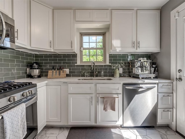 kitchen with marble finish floor, light countertops, white cabinets, a sink, and appliances with stainless steel finishes