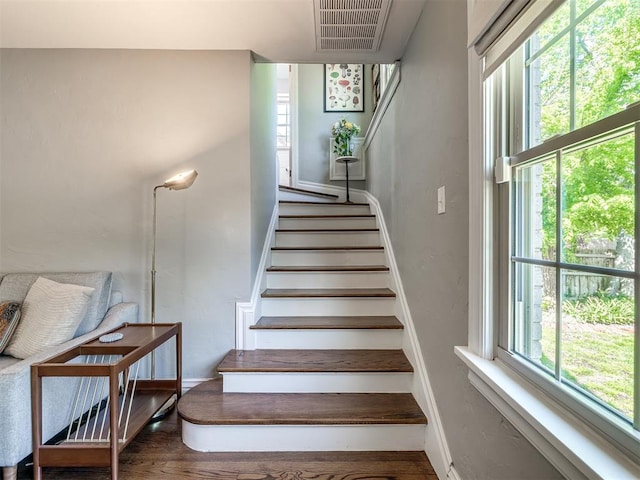 staircase with baseboards, wood finished floors, and visible vents