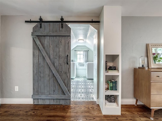 interior space featuring a barn door, vaulted ceiling, and wood finished floors