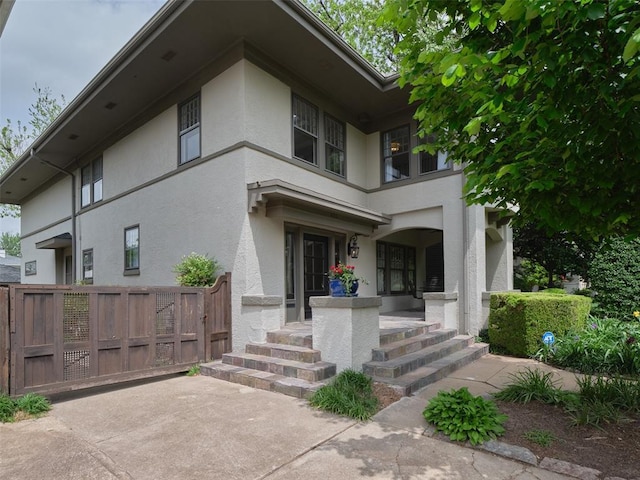 exterior space featuring covered porch, fence, and stucco siding
