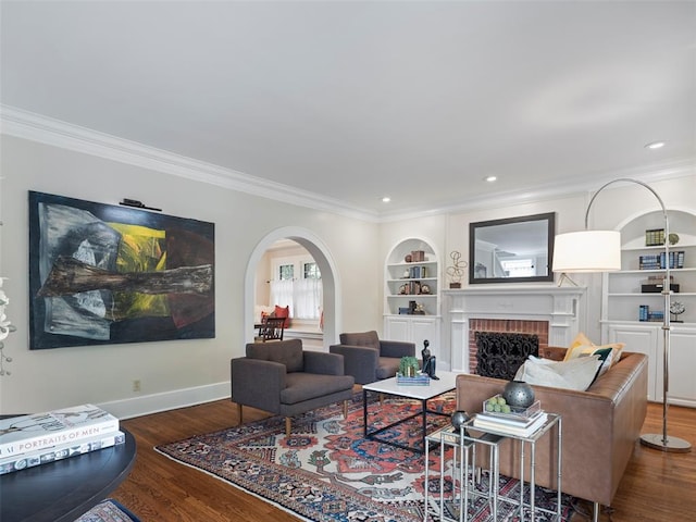 living room with ornamental molding, built in features, a fireplace, baseboards, and arched walkways