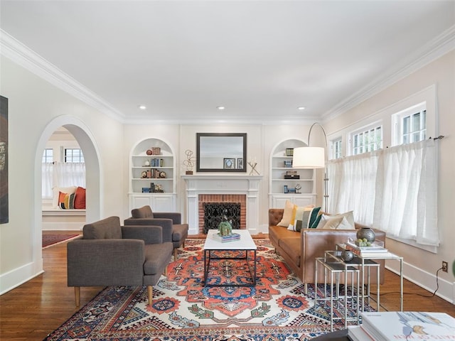 living room with built in features, baseboards, ornamental molding, and wood finished floors
