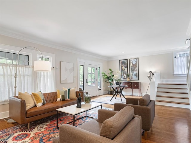 living room featuring baseboards, ornamental molding, wood finished floors, and stairway