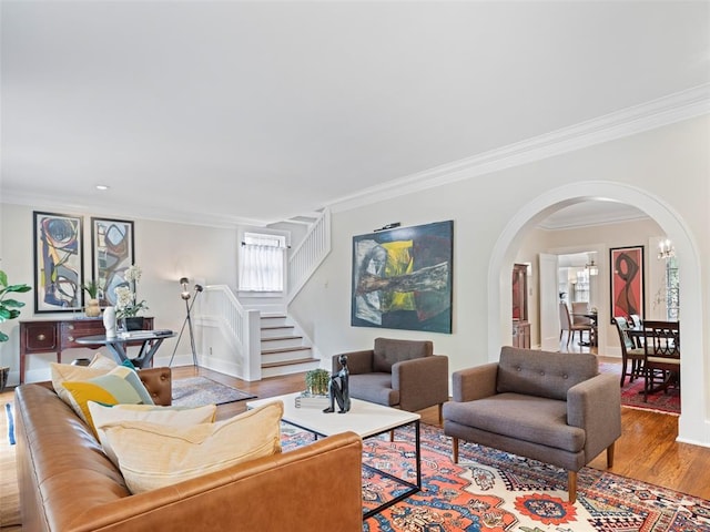 living room with ornamental molding, stairs, arched walkways, and wood finished floors