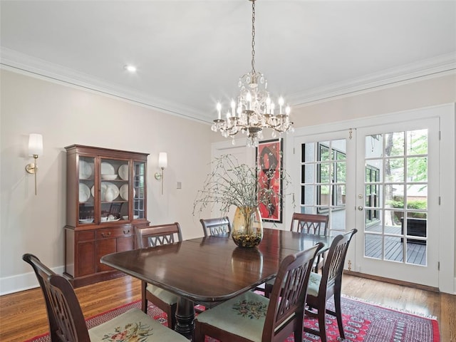 dining area with crown molding, baseboards, wood finished floors, and a chandelier