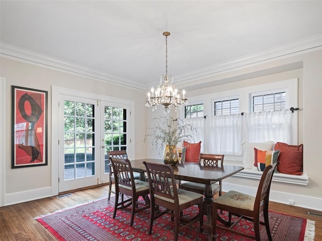 dining room with visible vents, ornamental molding, wood finished floors, baseboards, and a chandelier