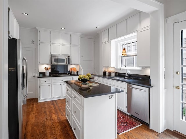 kitchen featuring dark countertops, appliances with stainless steel finishes, a sink, dark wood finished floors, and white cabinetry