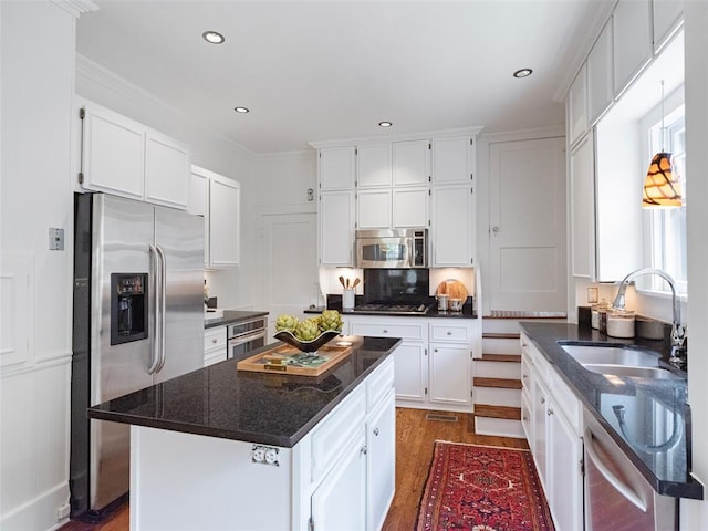 kitchen featuring dark wood-style floors, a center island, white cabinets, a sink, and appliances with stainless steel finishes