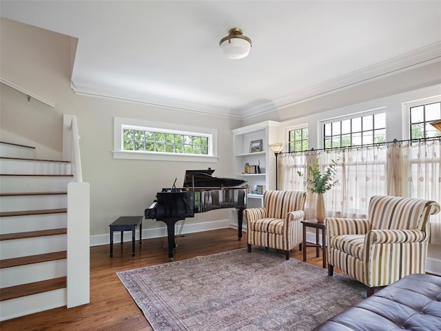 sitting room featuring stairway, ornamental molding, wood finished floors, and a wealth of natural light