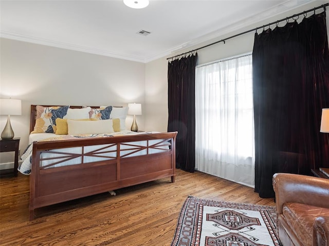 bedroom featuring crown molding, wood finished floors, and visible vents