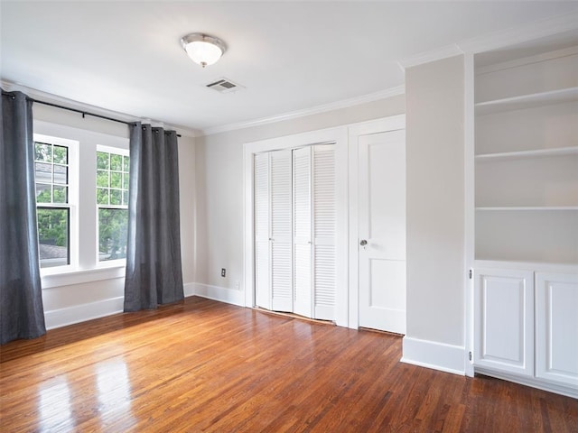 unfurnished bedroom with crown molding, baseboards, visible vents, and wood finished floors