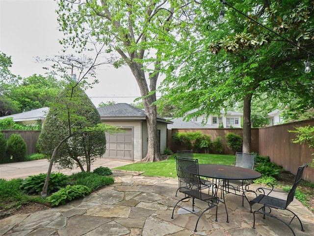 view of patio featuring fence, an outbuilding, outdoor dining area, and a garage