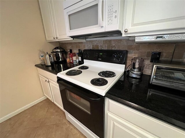 kitchen with range with electric stovetop, backsplash, baseboards, white microwave, and white cabinetry