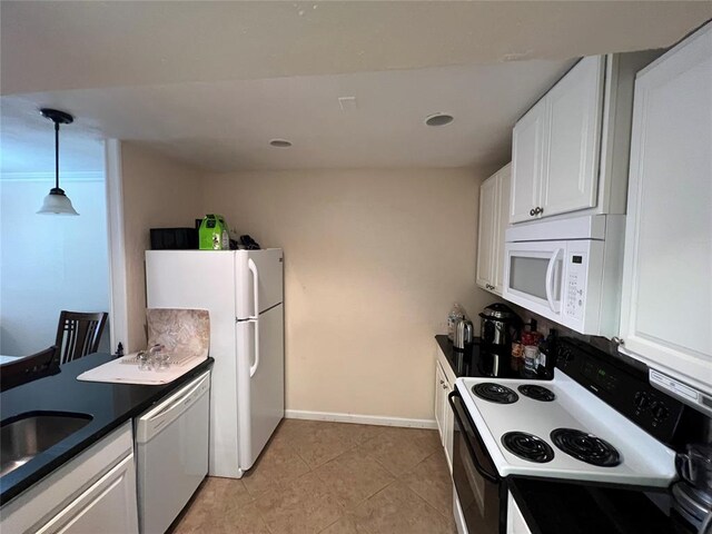 kitchen featuring dark countertops, light tile patterned floors, a sink, white appliances, and white cabinetry