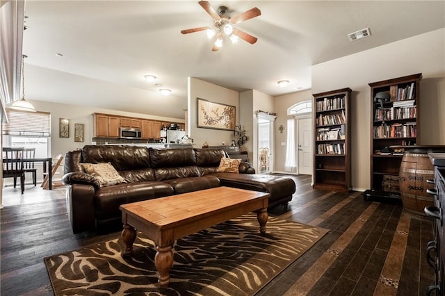 living area featuring dark wood-style flooring, ceiling fan, visible vents, and lofted ceiling