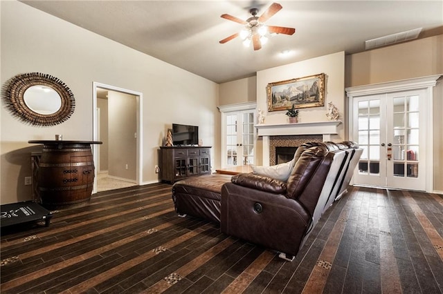 living area featuring a ceiling fan, french doors, visible vents, a fireplace, and wood-type flooring