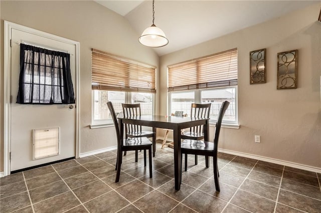 dining area featuring baseboards, vaulted ceiling, and dark tile patterned flooring