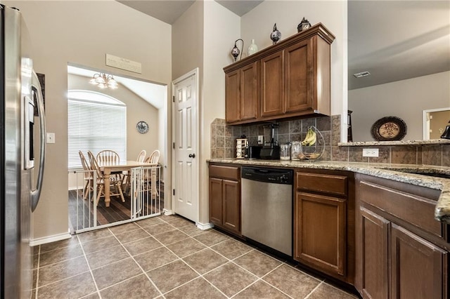kitchen with baseboards, tasteful backsplash, a sink, a notable chandelier, and stainless steel appliances