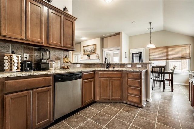 kitchen with dark tile patterned floors, vaulted ceiling, dishwasher, a sink, and a peninsula