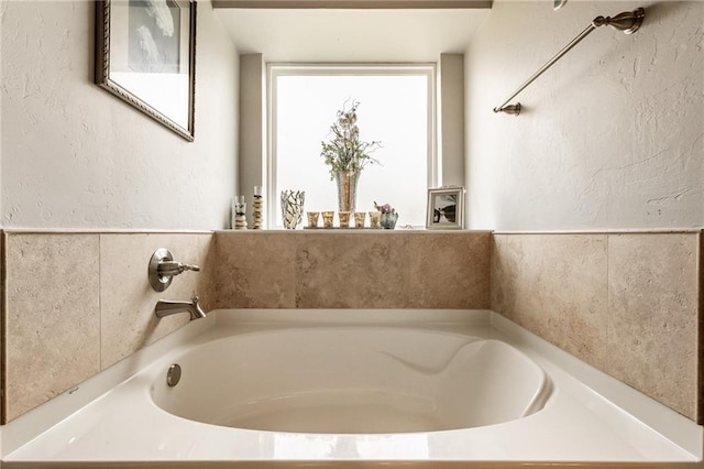 bathroom with a textured wall and a garden tub