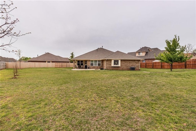 back of house with a yard, a fenced backyard, and a patio area