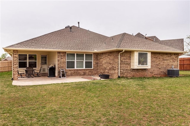rear view of house with roof with shingles, a patio area, brick siding, central AC, and fence