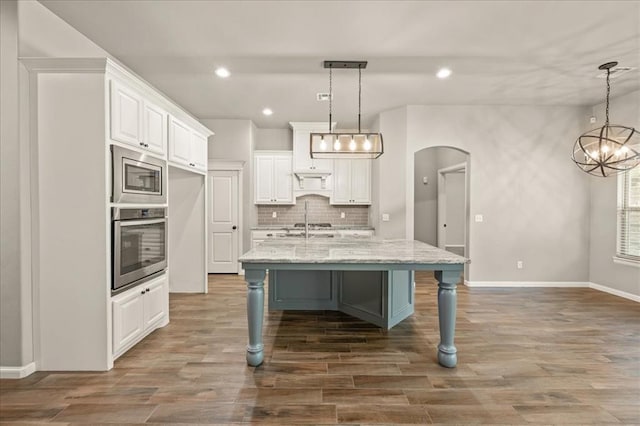 1016 NW 191st St, Edmond, OK 73012 - kitchen featuring decorative backsplash, stainless steel appliances, arched walkways, and white cabinetry