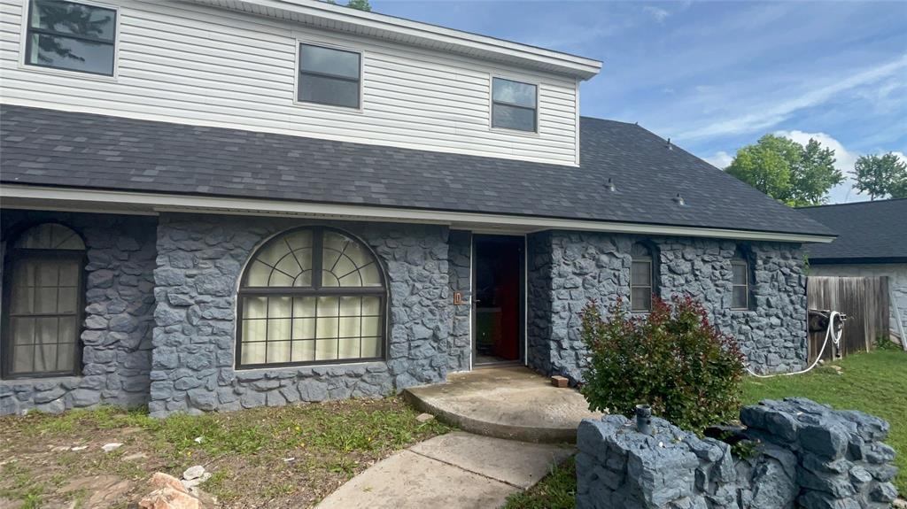 entrance to property with a shingled roof and stone siding