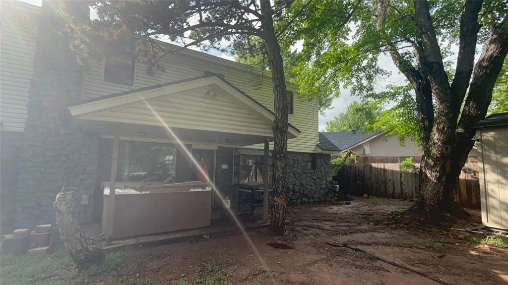 rear view of house with fence, a jacuzzi, and stone siding
