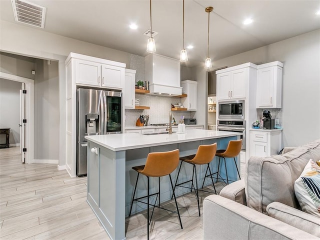 kitchen with backsplash, stainless steel appliances, open floor plan, and visible vents