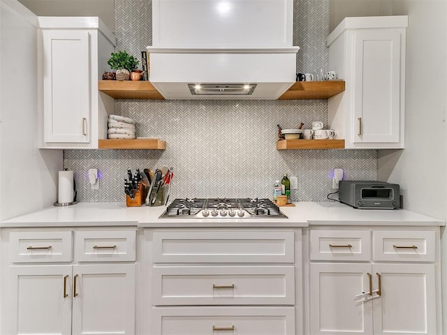 kitchen featuring stainless steel gas stovetop, decorative backsplash, open shelves, and custom range hood